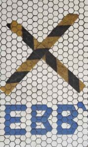 A photo of a white tiled floor marked with a croos during covid lockdown